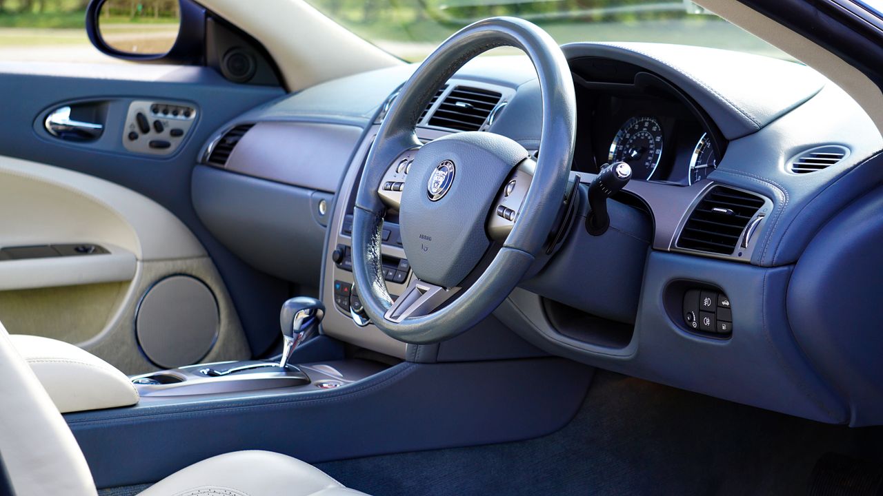 Elegant interior of luxury car featuring steering wheel and dashboard.