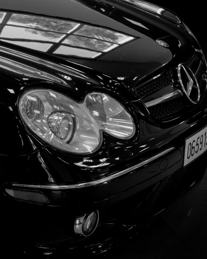 Elegant black Mercedes Benz with shining headlights, close-up shot highlighting luxury and design.